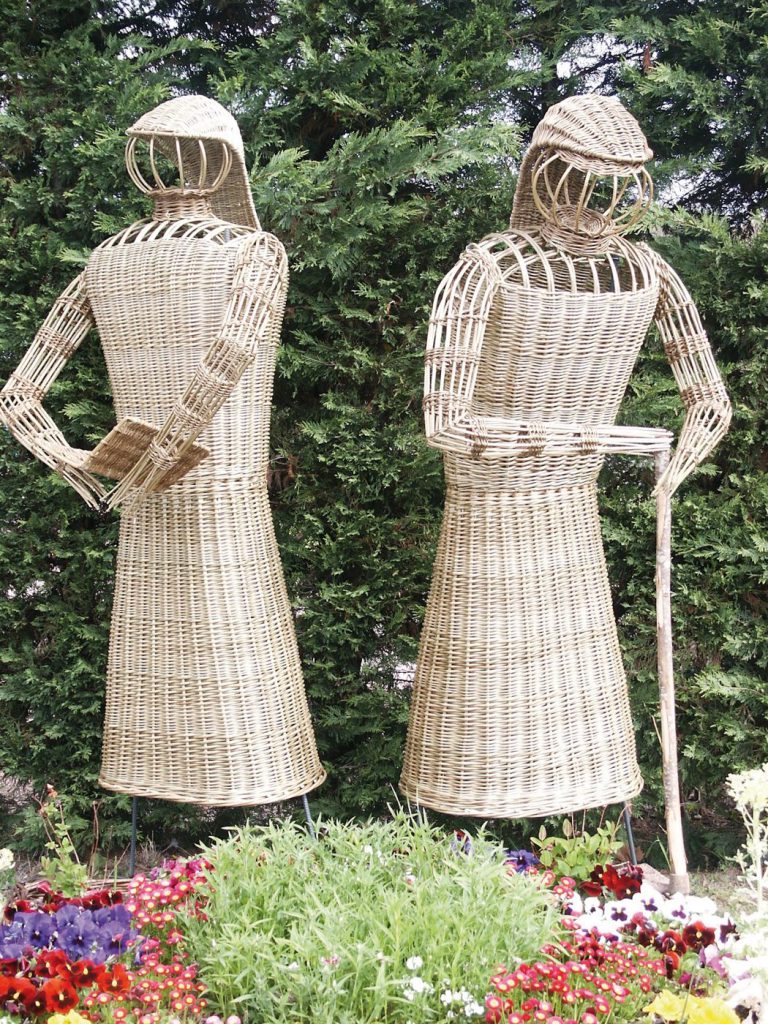 Statues en osier dans un massif de fleurs